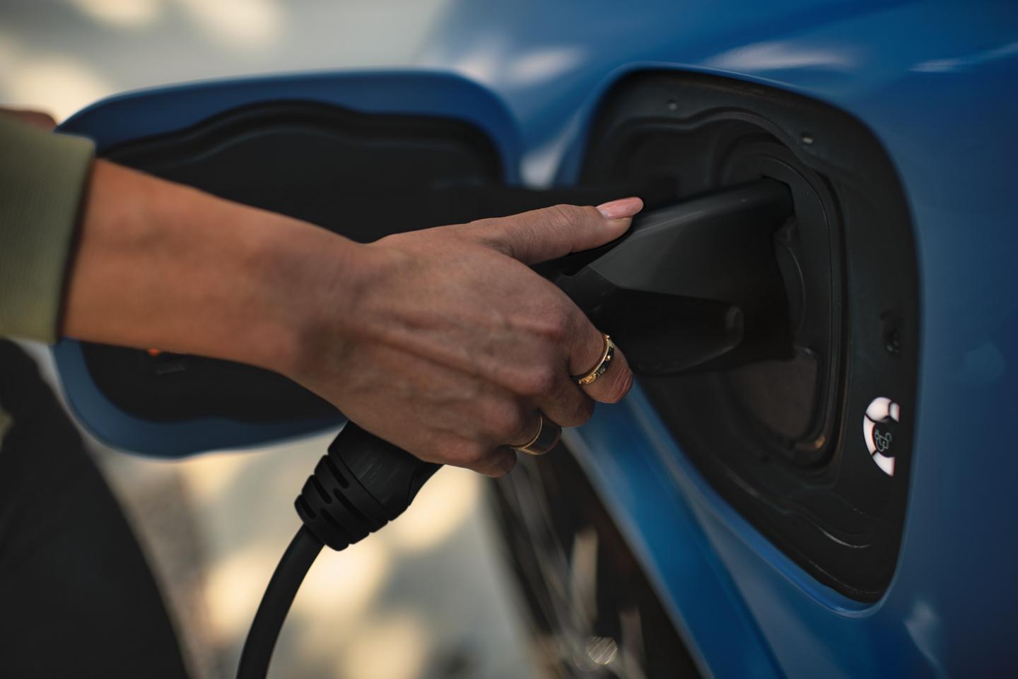 Une personne branche un chargeur à un VÉ Ford.