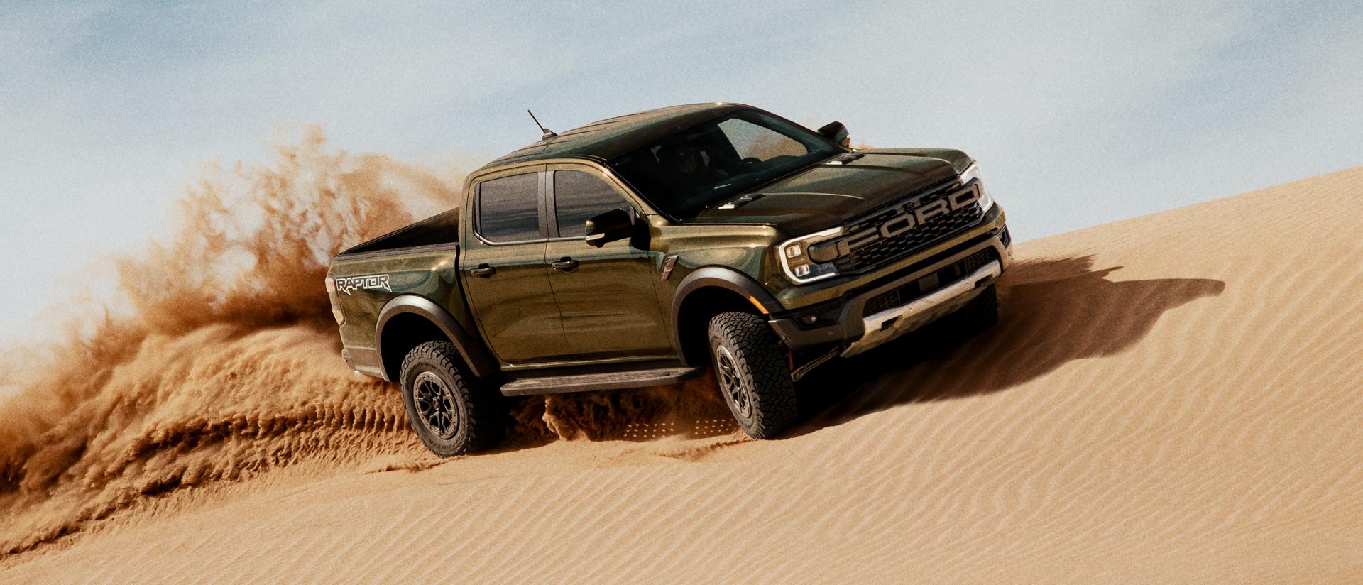 Un modèle Ranger® Raptor® 2025 circulant sur une dune de sable et projetant du sable