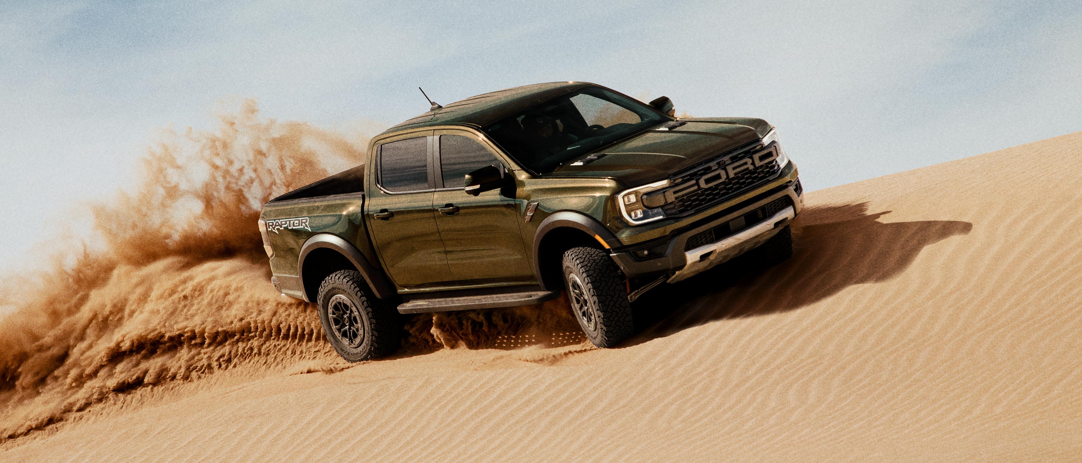Un modèle Ford Ranger® Raptor® 2025 circulant sur une dune de sable et projetant du sable