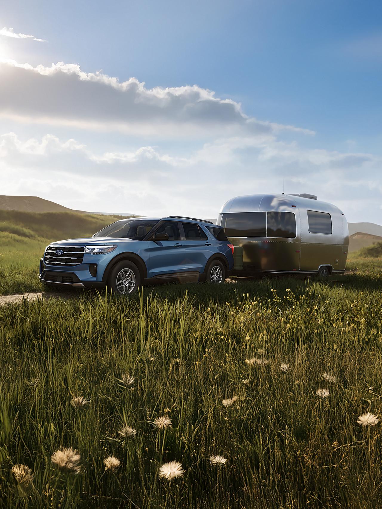 Un modèle Ford Explorer® Active 2027, attelé à une remorque de voyage, prêt pour l’aventure au cœur de la nature