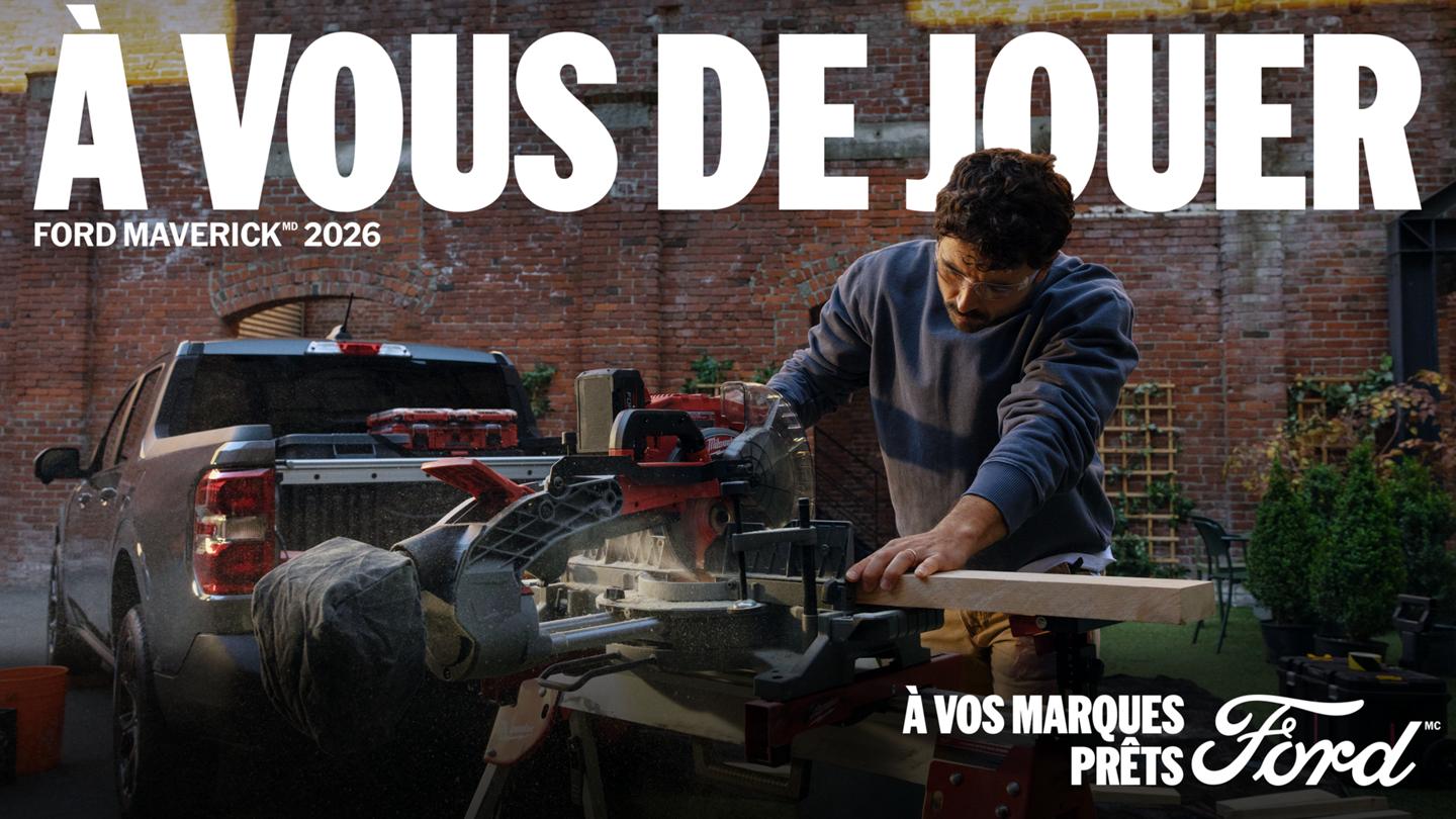 Un homme coupe du bois avec une scie à onglets électrique devant un camion Ford Maverick 2026 de couleur gris carbonisé près d’un édifice en briques. On peut lire le titre « À VOUS DE JOUER ».