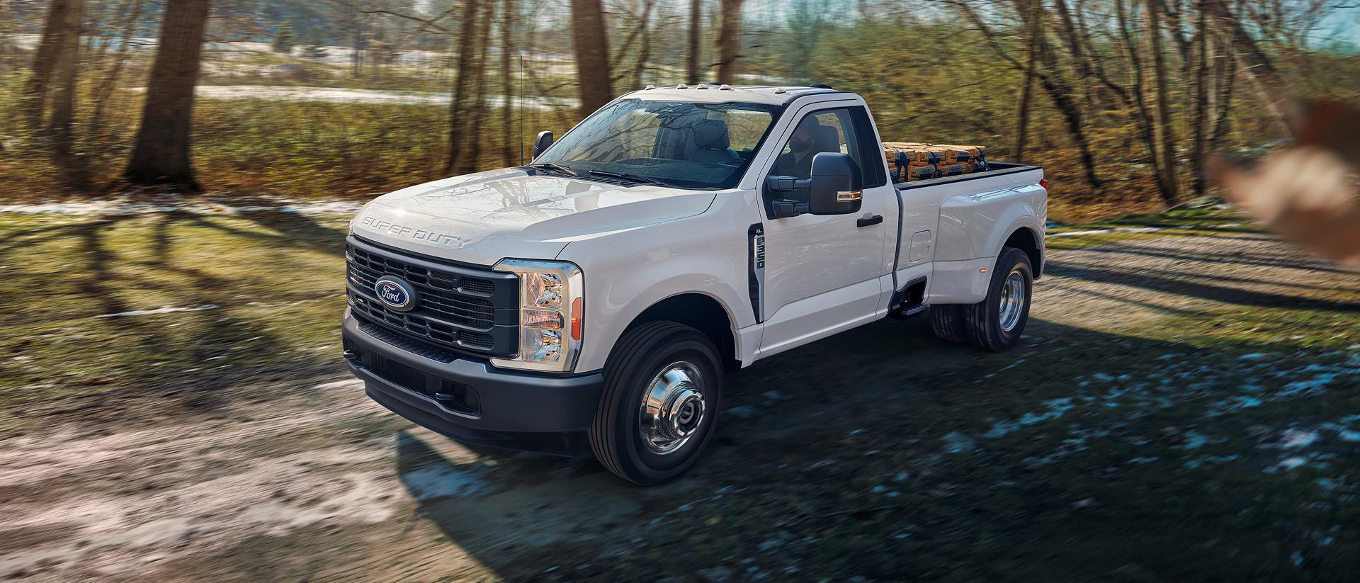 Ford Super Duty® F-350® XL 2026 circulant sur une route de terre avec une caisse de camion pleine
