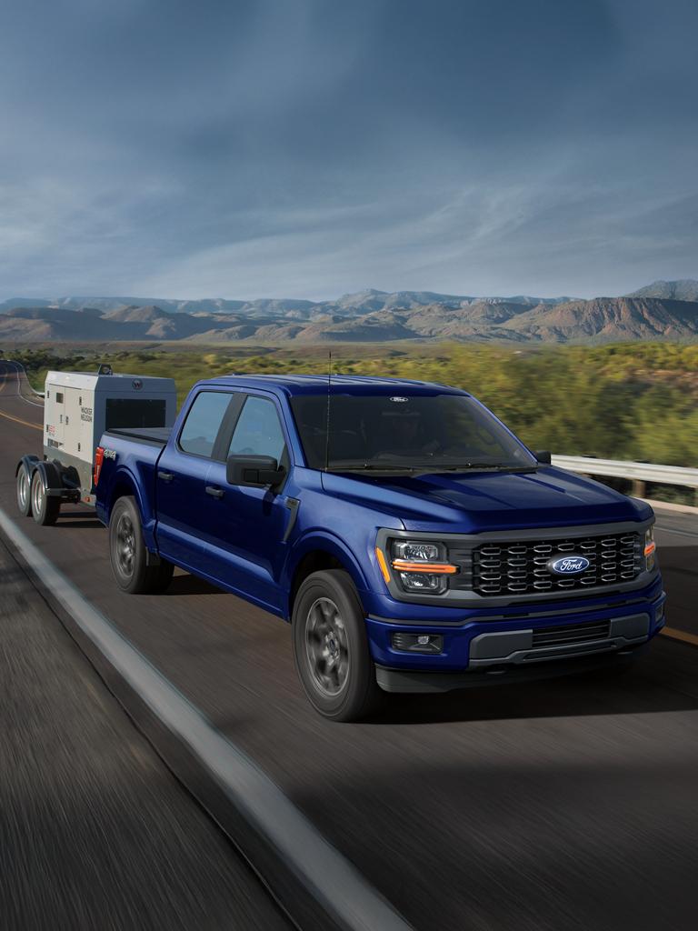 Modèle Ford F-150® STX® 2026 en bleu Argon métallisé tirant une petite remorque