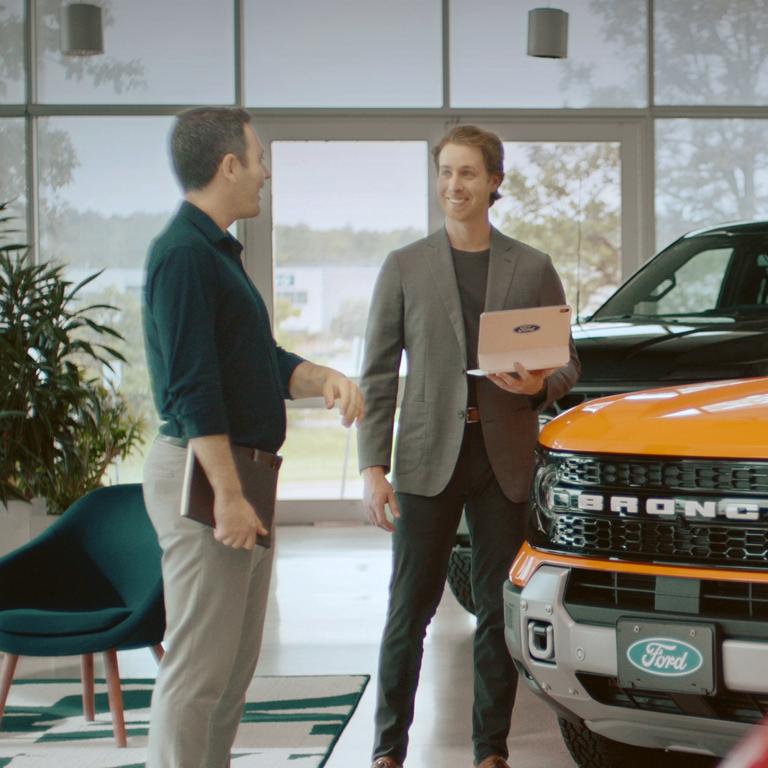 Deux personnes discutent à côté d'un véhicule Ford.