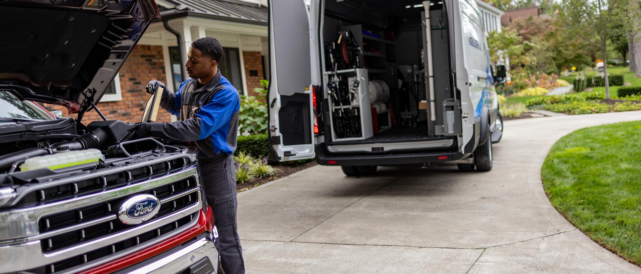 Un technicien de Service Ford travaille sur un véhicule. Le fourgon du service d’entretien mobile est visible en arrière-plan.
