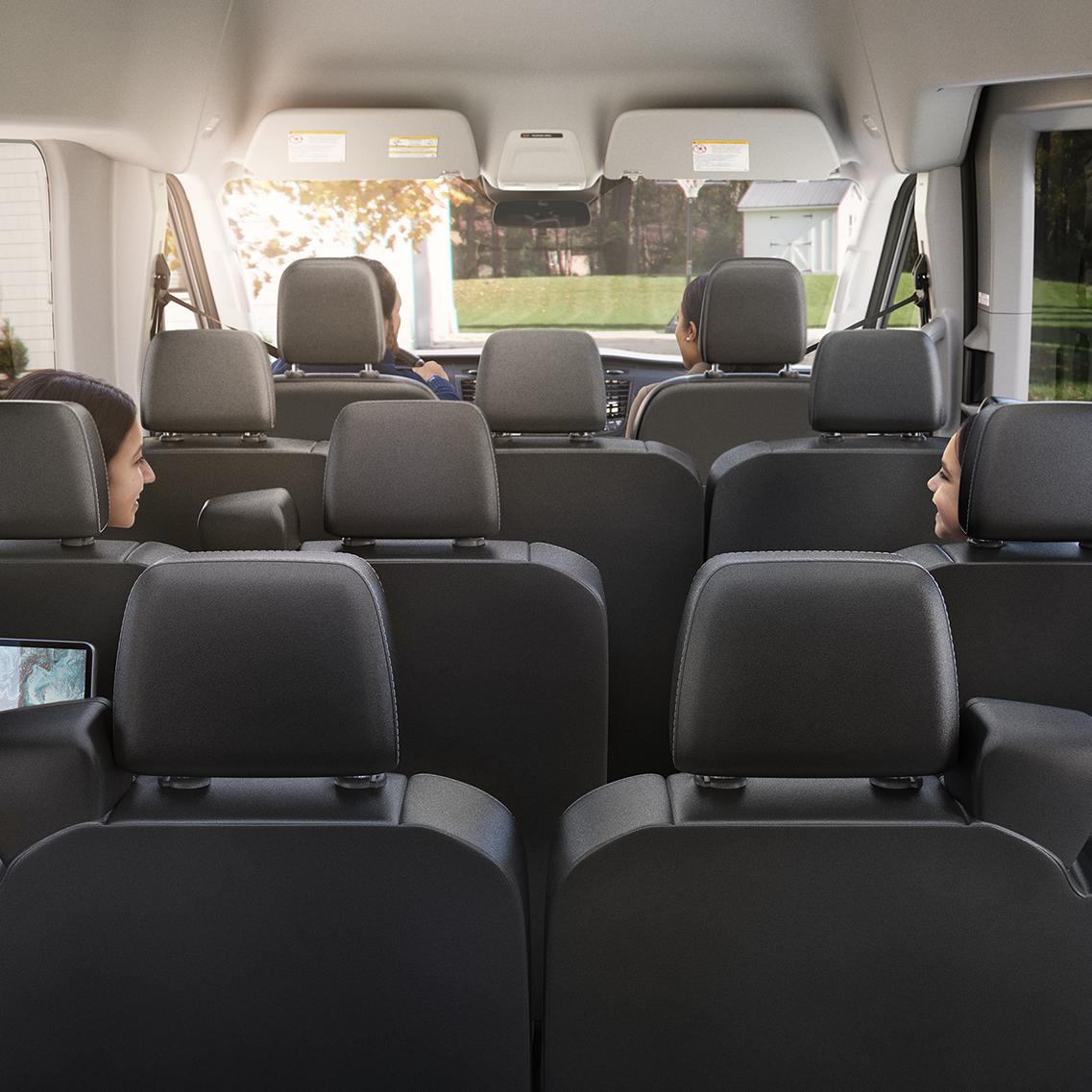Vue arrière de l'intérieur du Ford Transit avec tous les sièges en position verticale et quatre passagers à l'intérieur.