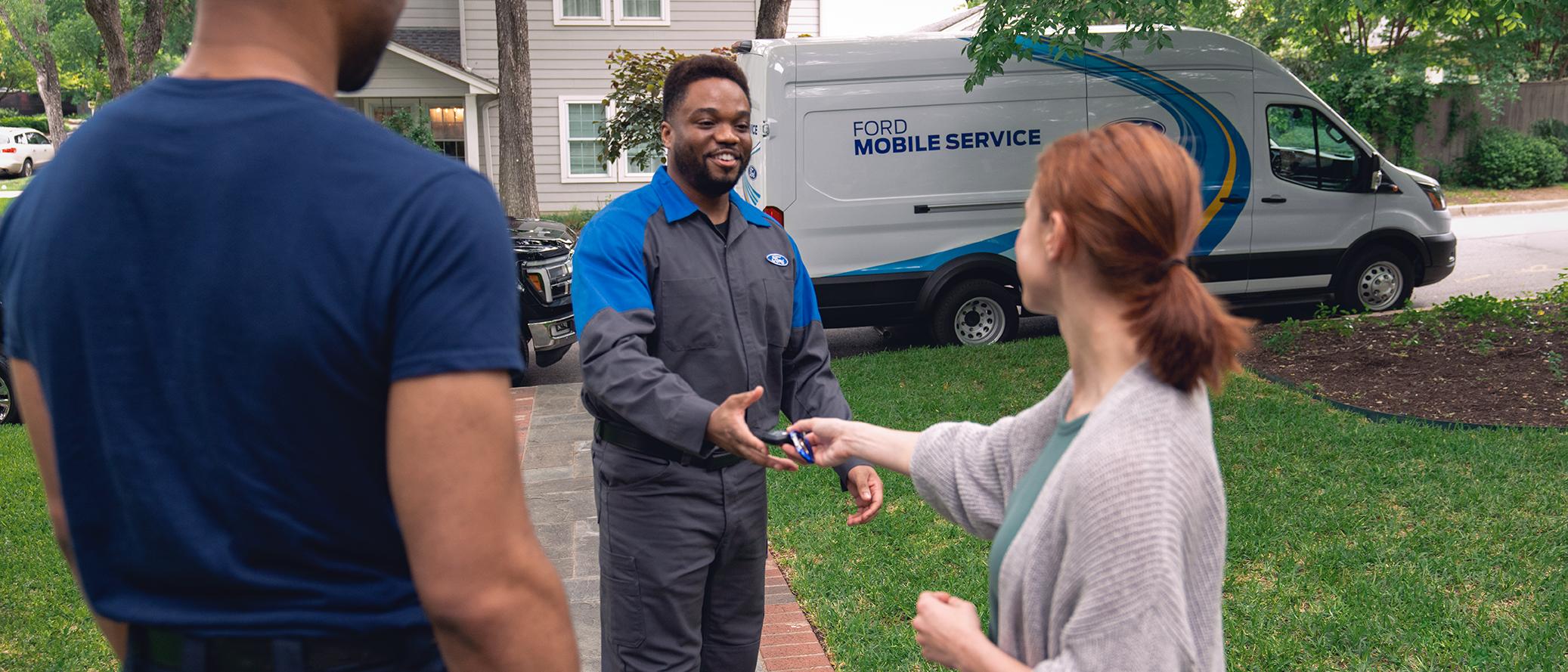 Une propriétaire Ford remet ses clés à un technicien du service d’entretien mobile Ford devant sa maison.