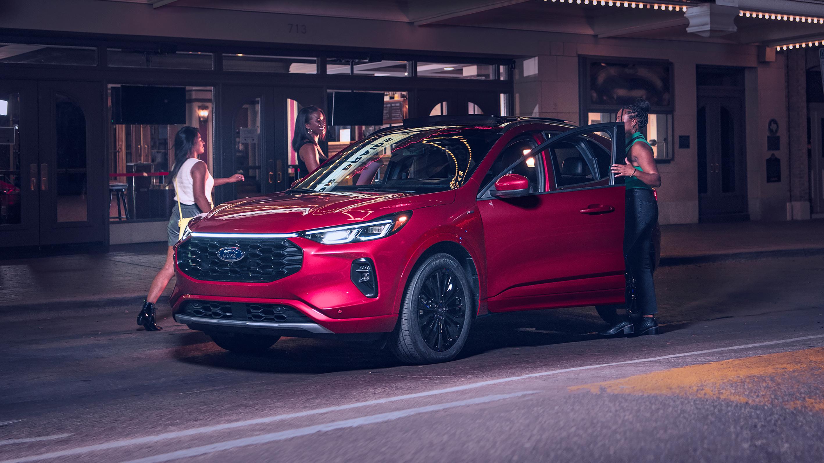 Un groupe d'amis monte de nuit dans un VUS Ford Escape® 2025 rouge