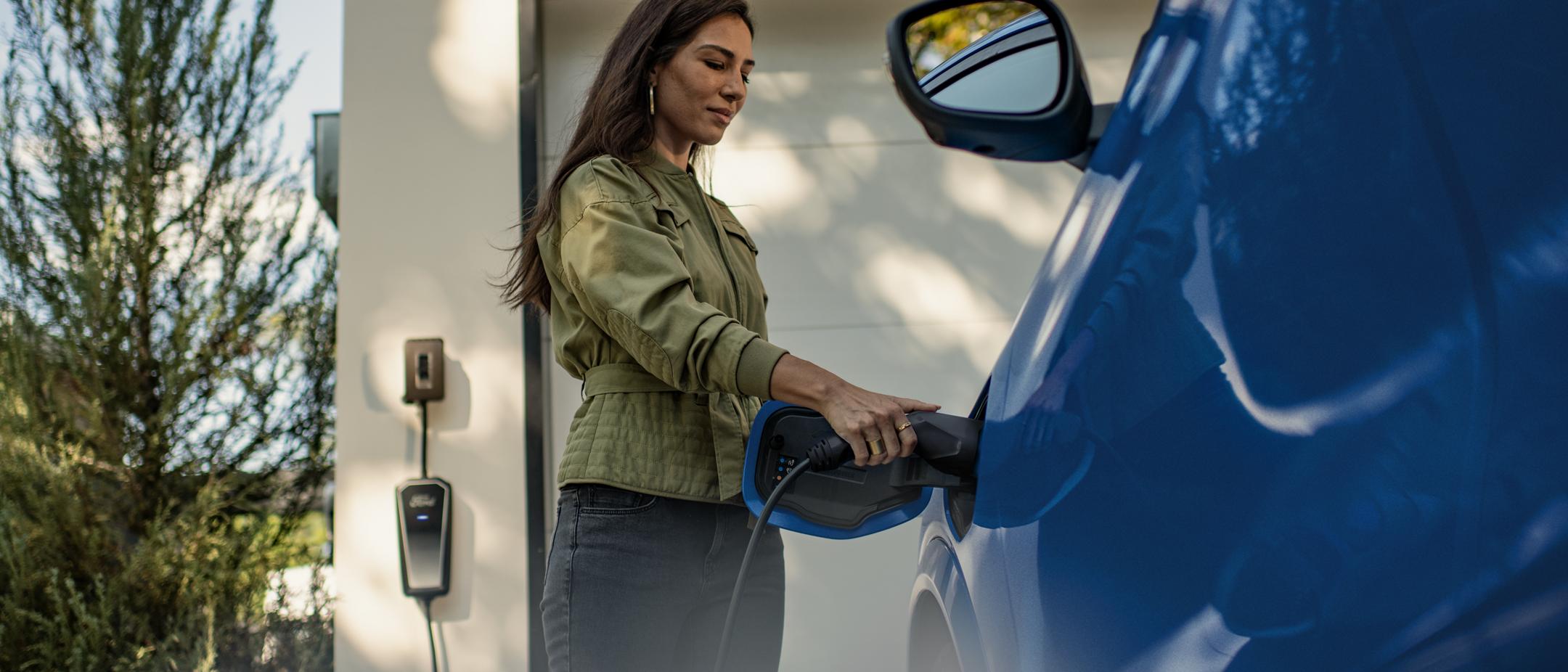 Une personne branche une Mustang Mach-E à une borne de recharge.