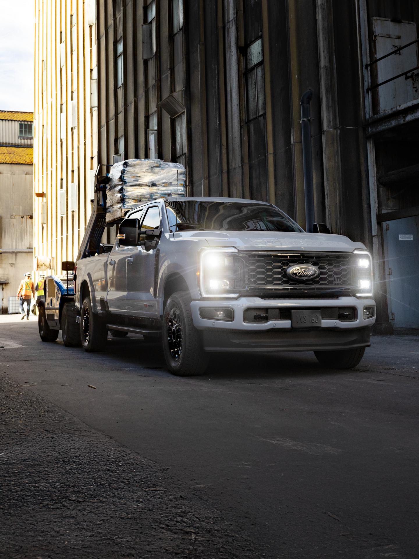 Un Super Duty garé sur un chantier, avec une remorque attelée chargée de tubes en acier.