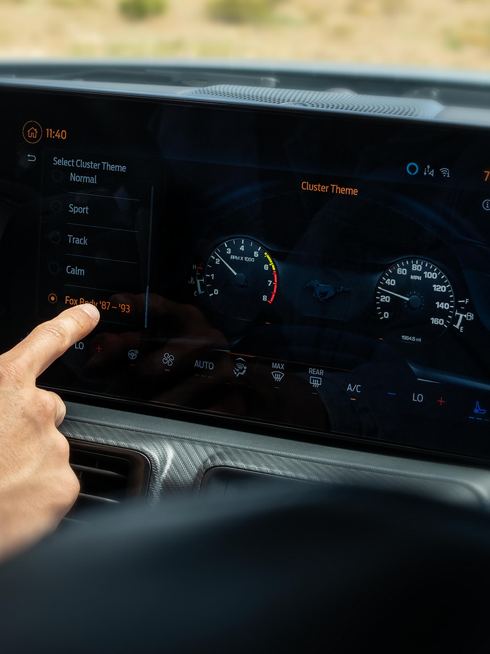 Personne utilisant l’écran central de la Ford Mustang® fastback 2026 avec l’écran courbé panoramique avec cadre en magnésium en option