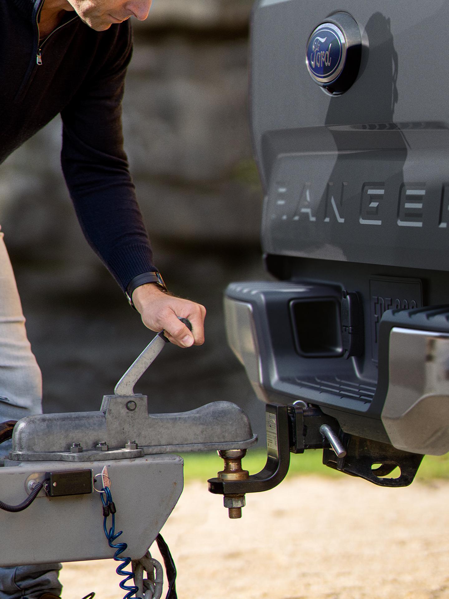 La main d’une personne utilise l’ensemble de remorquage en option pour atteler une remorque à son camion Ford Ranger® XL 2026