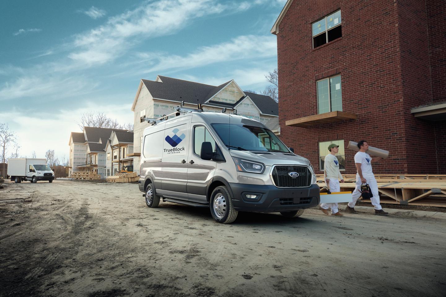 Deux travailleurs marchant à côté d’une fourgonnette Ford Transit® 2026 stationnée sur un chantier de construction