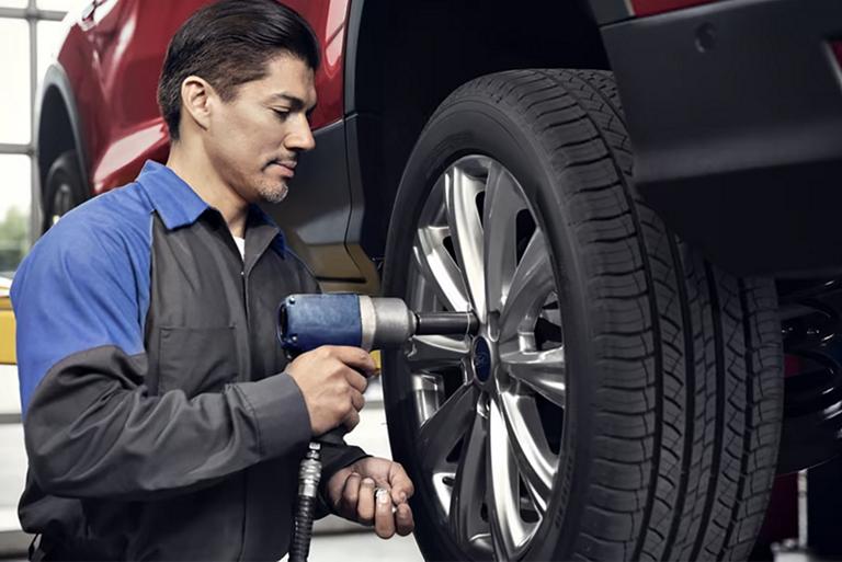 Un technicien de Service Ford retire des écrous d’un véhicule Ford sur un pont élévateur.