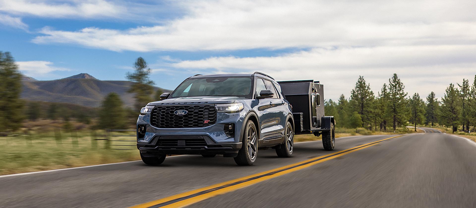 Un VUS Ford Explorer® 2027 tirant une caravane sur une autoroute à travers le collines