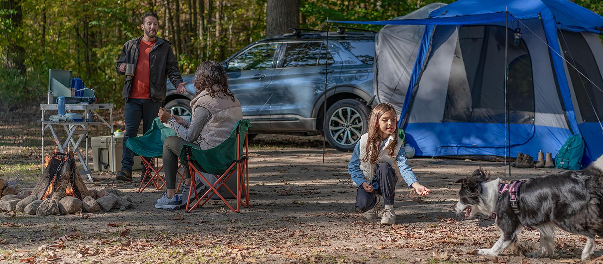 Une famille et son chien faisant du camping près d’un VUS Ford Explorer® 2027 stationné
