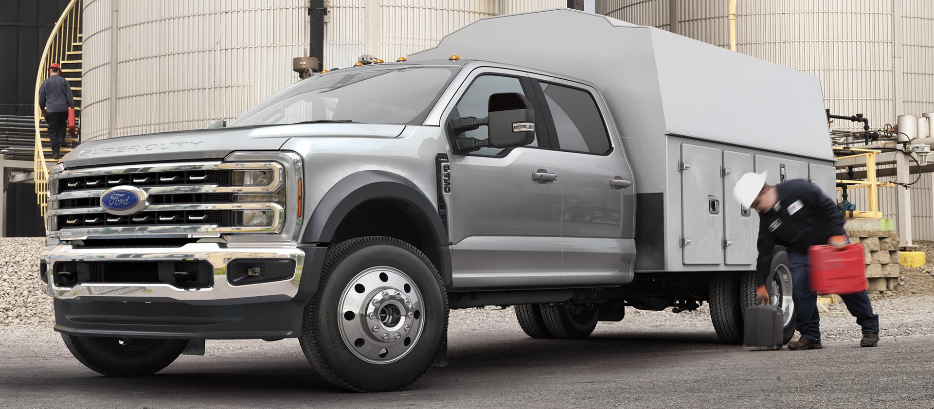 Un travailleur ramassant de l’équipement devant le caisson de service de son Ford Super Duty® à châssis-cabine 2026