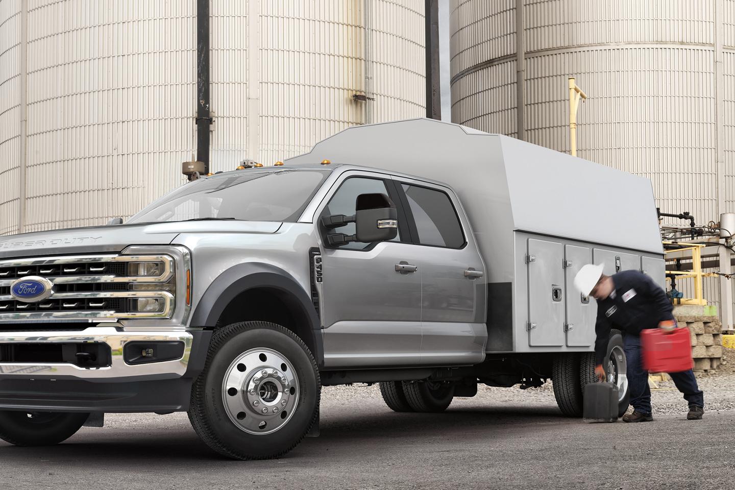 Un travailleur ramassant de l’équipement devant le caisson de service de son Ford Super Duty® à châssis-cabine 2026