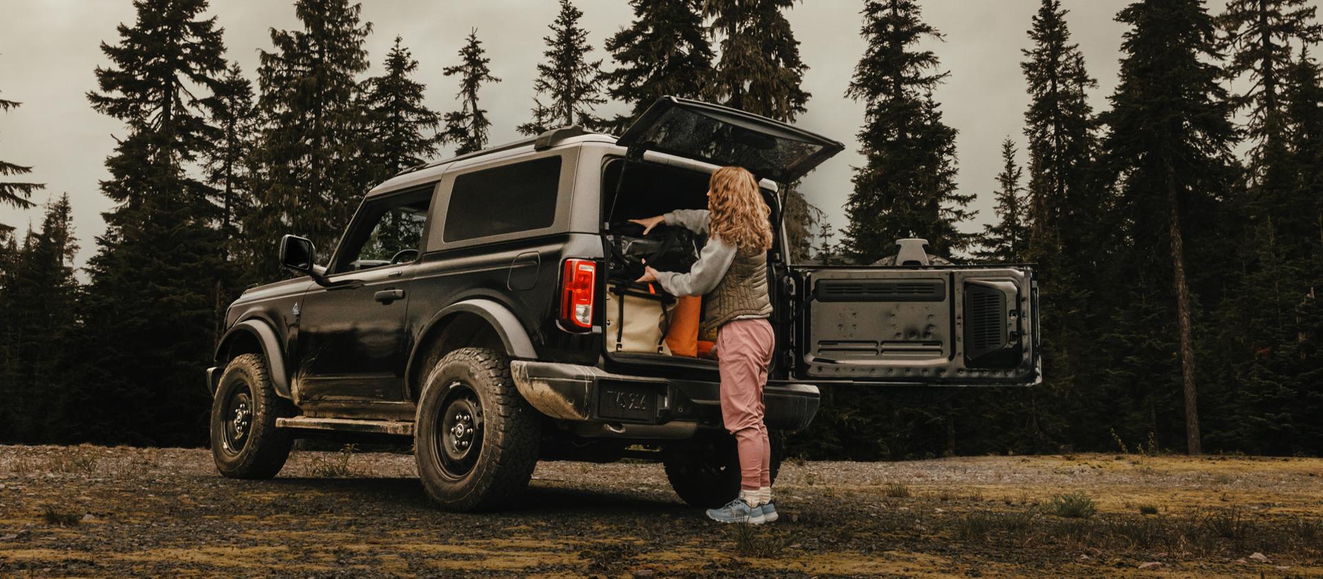 Une femme déchargeant de l’équipement de l’arrière d’un VUS Ford Bronco® 2025, montrant le hayon à ouverture latérale