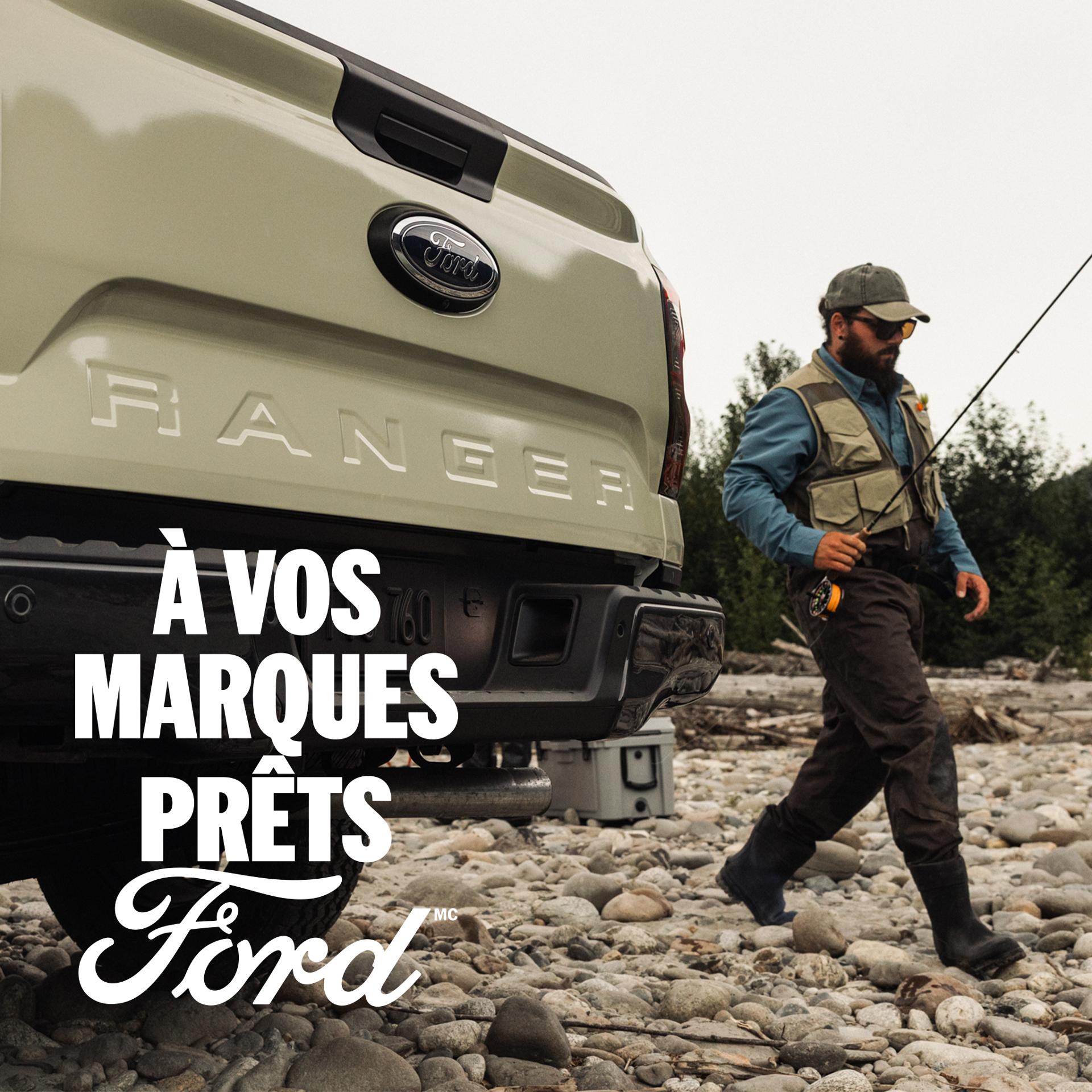 Une personne passant devant l’arrière de son camion Ford Ranger® 2026 avec une canne à pêche