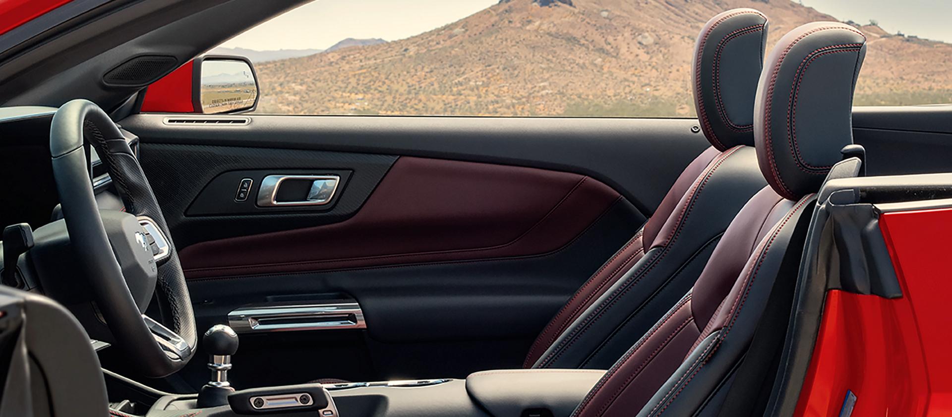 Ford Mustang® 2026 décapotable stationnée avec la portière du côté conducteur ouverte montrant l’intérieur rouge carmin en option