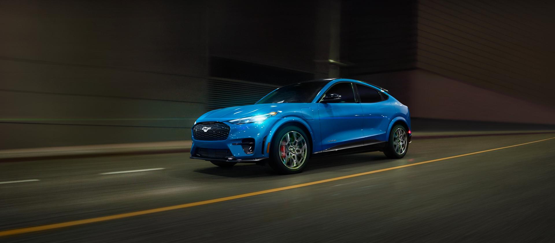 Ford Mustang Mach-E® 2025 circulant sur une autoroute avec la ville en arrière-plan flou