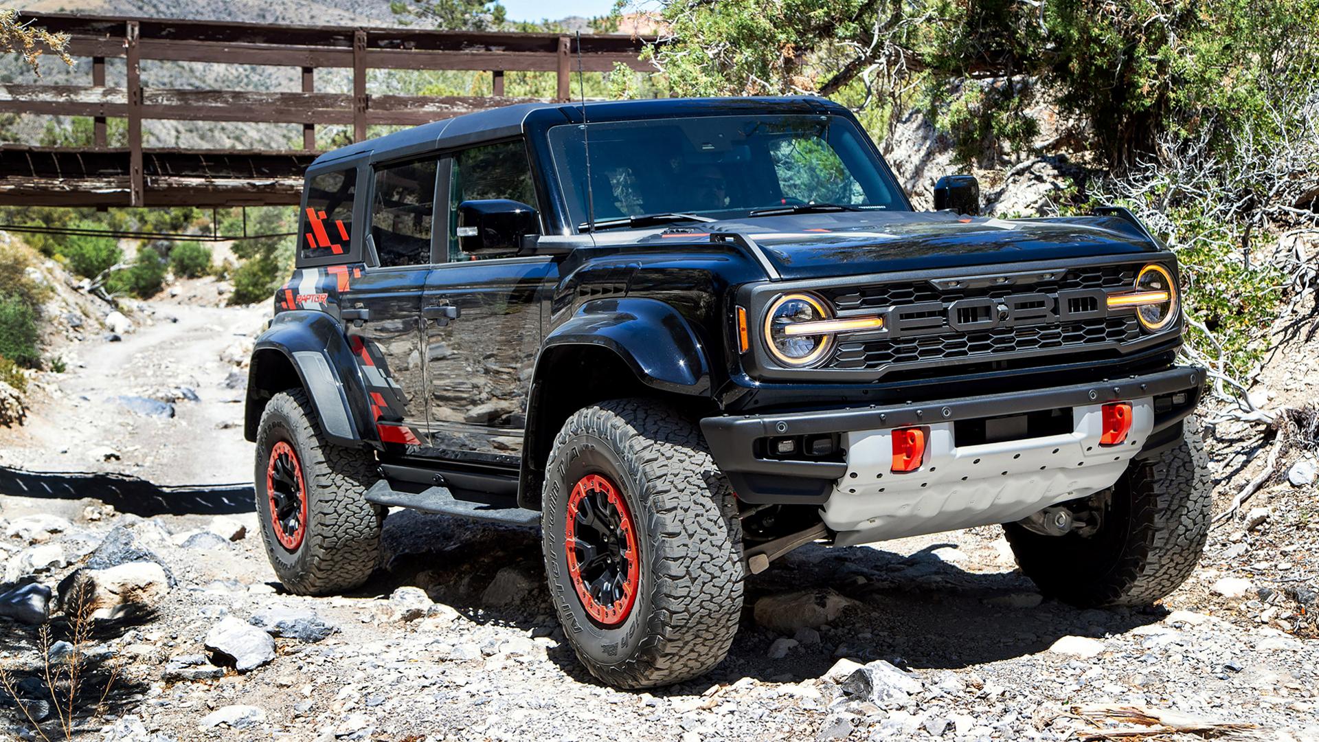 Un VUS Ford Bronco® Raptor® 2026 avec l’ensemble décor Code orange en option, garé sur un lit de ruisseau rocheux