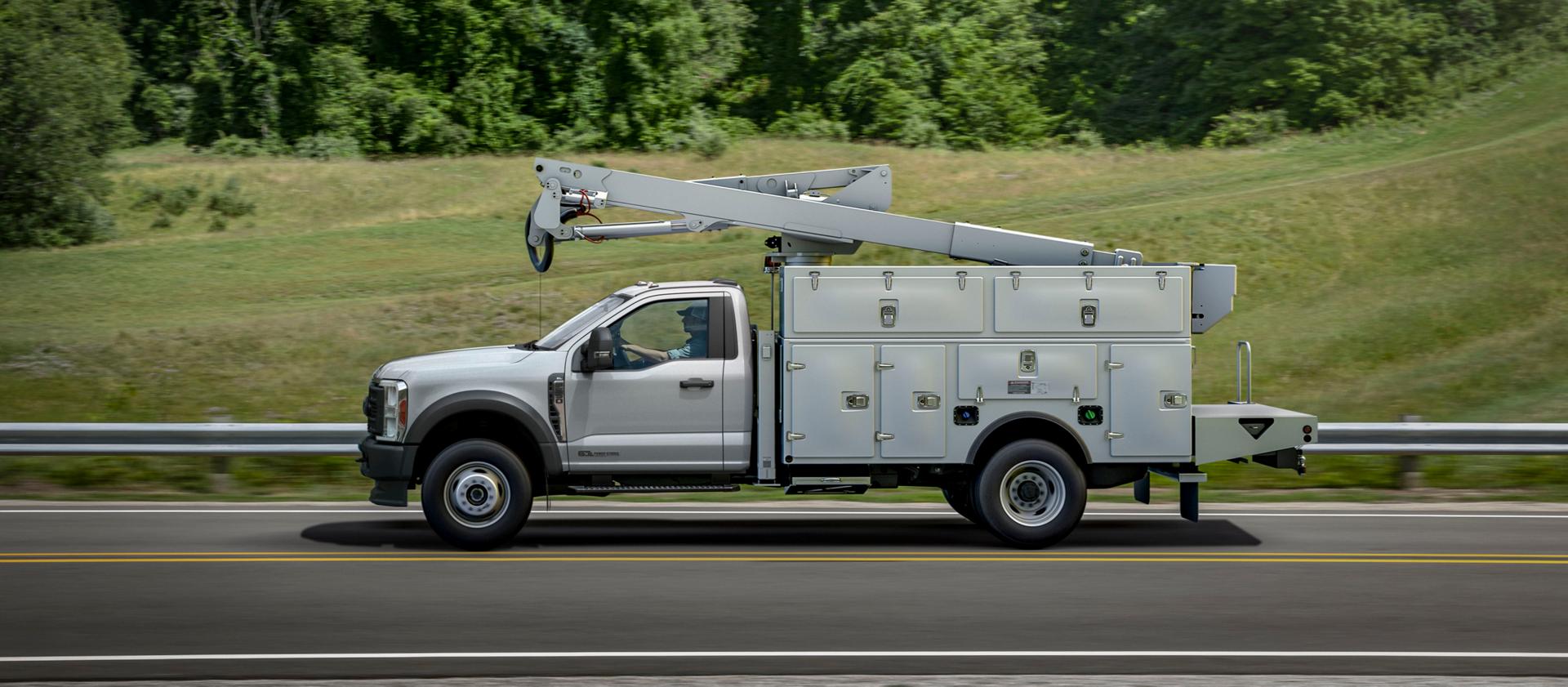 Un Ford Super Duty® à châssis-cabine 2026 avec une rallonge de flèche et un caisson utilitaire circulant sur une route