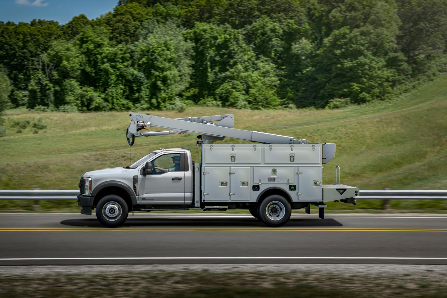 Un Ford Super Duty® à châssis-cabine 2026 avec une rallonge de flèche et un caisson utilitaire circulant sur une route