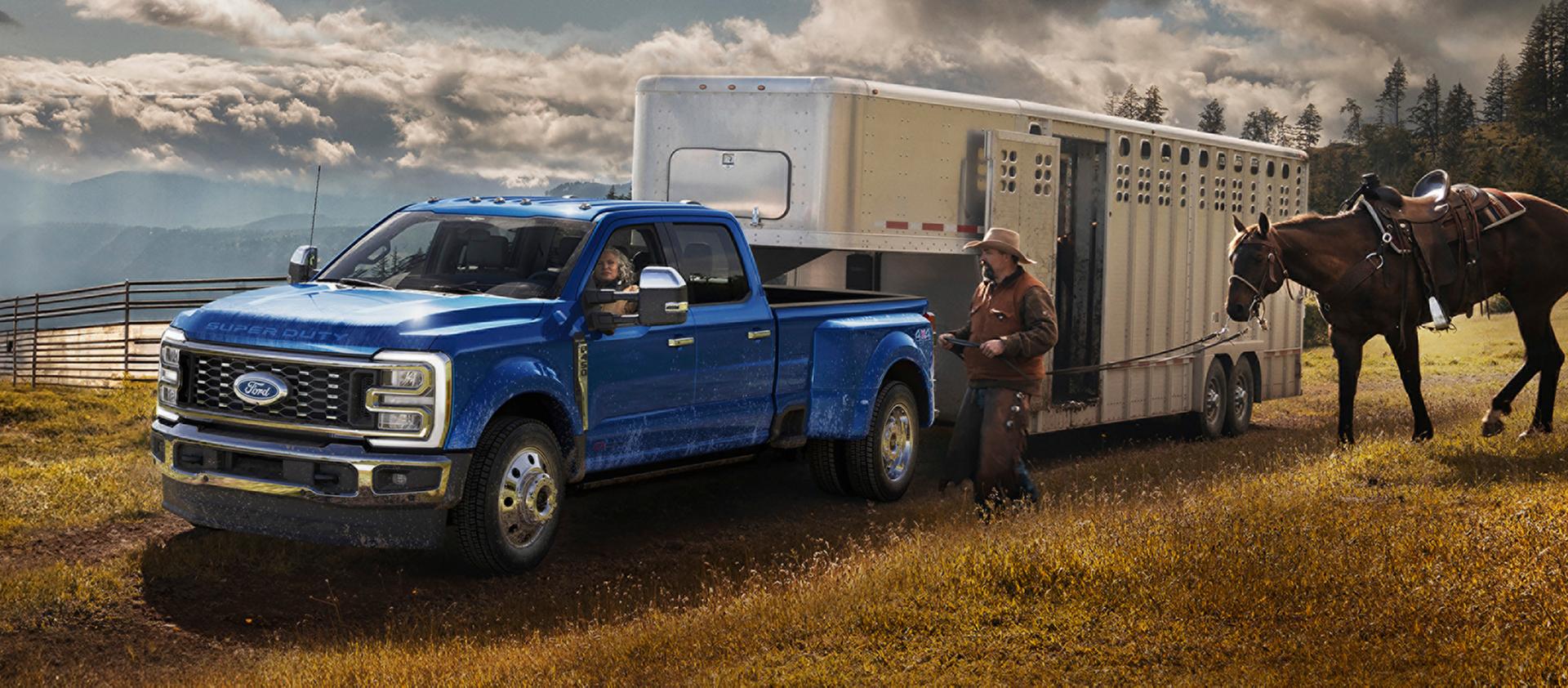 Camionnette Ford Super Duty® F-450® King Ranch® 2027 couleur bleu Neptune remorquant un transporteur de chevaux sur une ferme herbeuse