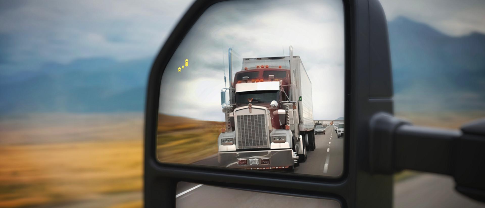 Vue du rétroviseur gauche d’un camion Ford Super Duty® 2027 avec un semi-remorque dans la réflexion.
