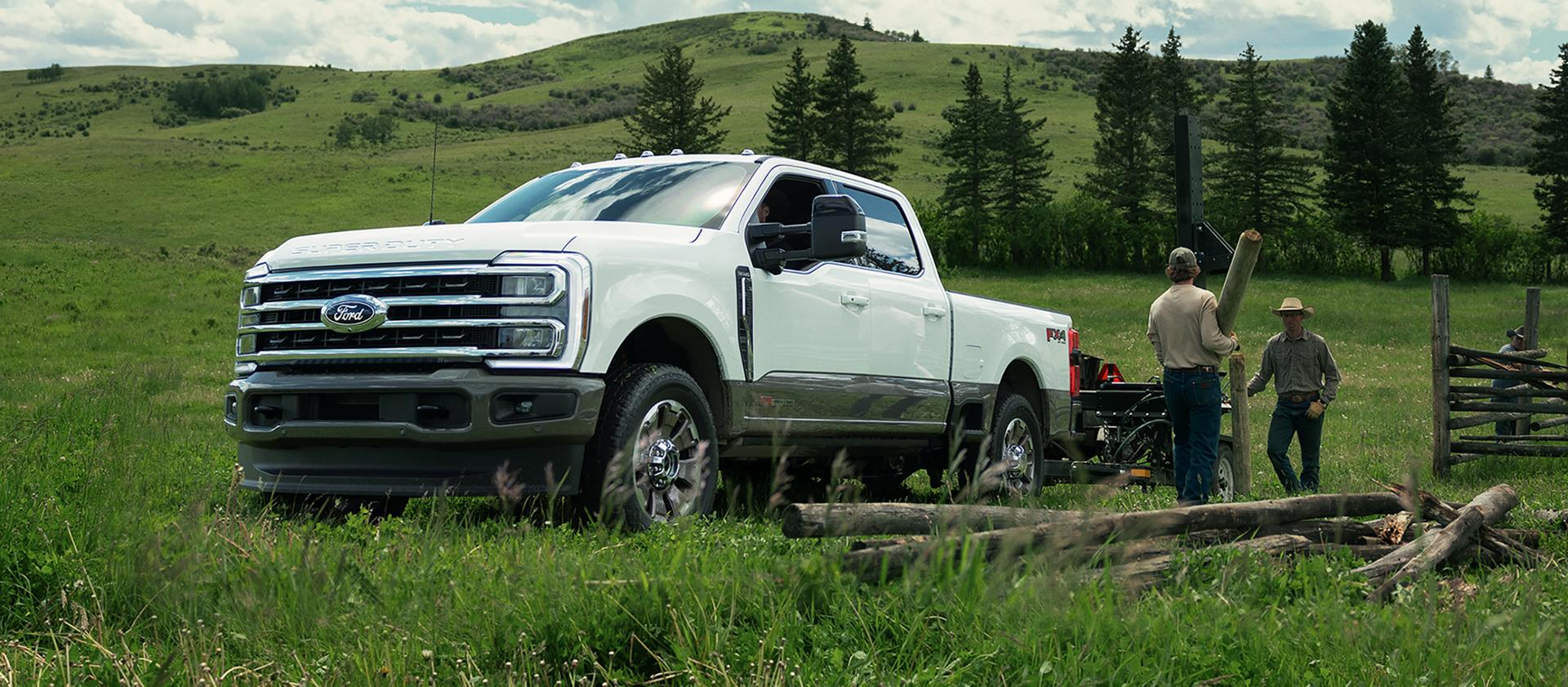 2027 Super Duty® F-350® King Ranch® model towing a trailer of lumber with two workers unloading the lumber from the trailer