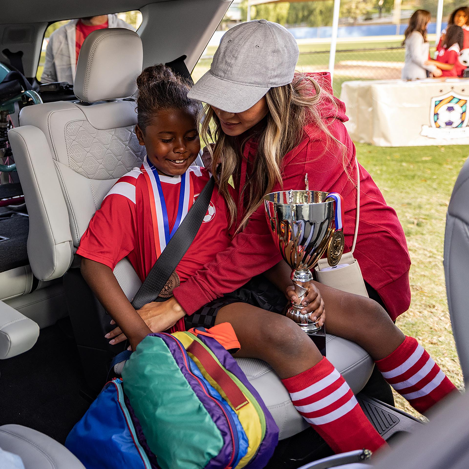 Un parent aidant à installer de jeunes joueurs de soccer sur les sièges de deuxième rangée d’un VUS Ford Explorer® 2027