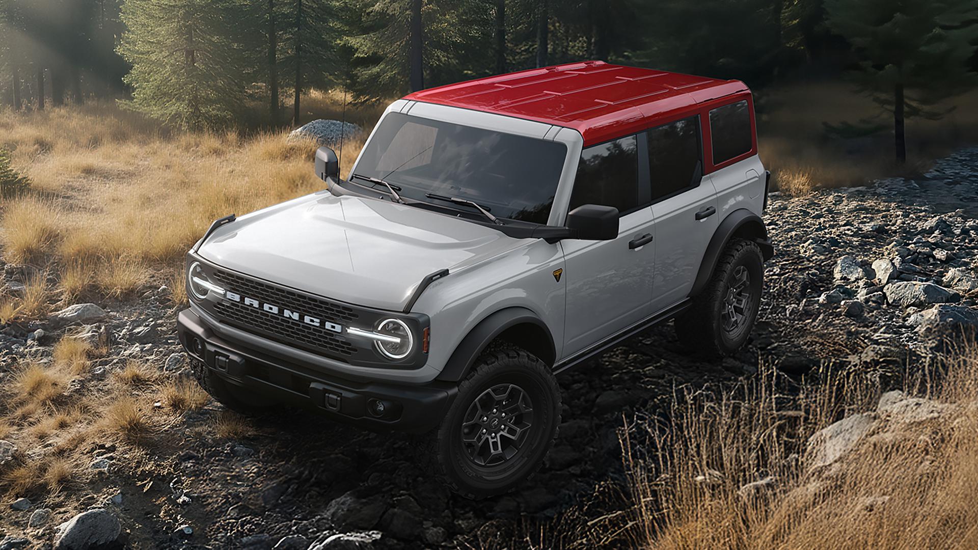 Un VUS Ford Bronco® 2026 sur un chemin boueux, avec une carrosserie gris Avalanche et un toit rouge