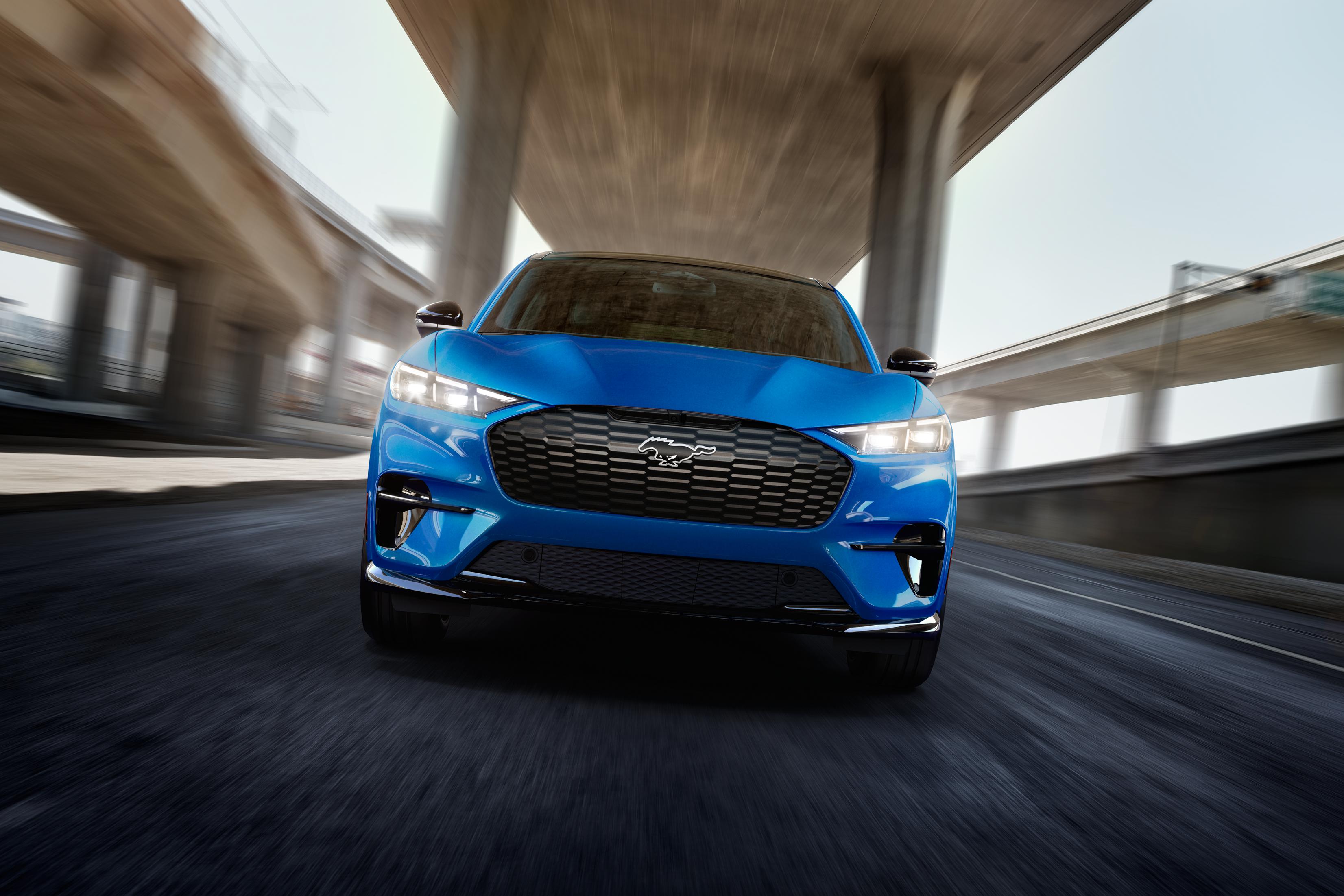 Vue avant d’un modèle Mustang Mach-E® GT 2025 conduit sur une autoroute avec un arrière-plan flou