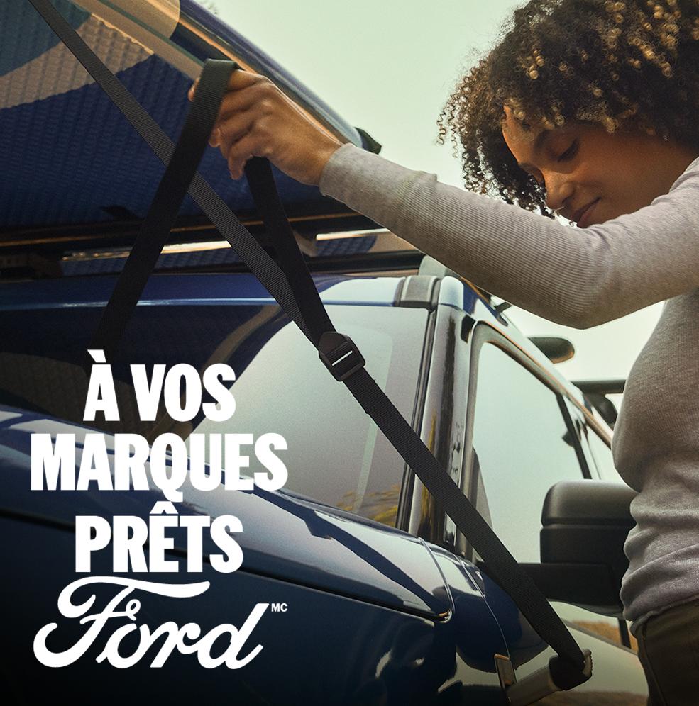 Une personne fixant une planche à rame sur le toit du VUS Ford Bronco Sport® 2026