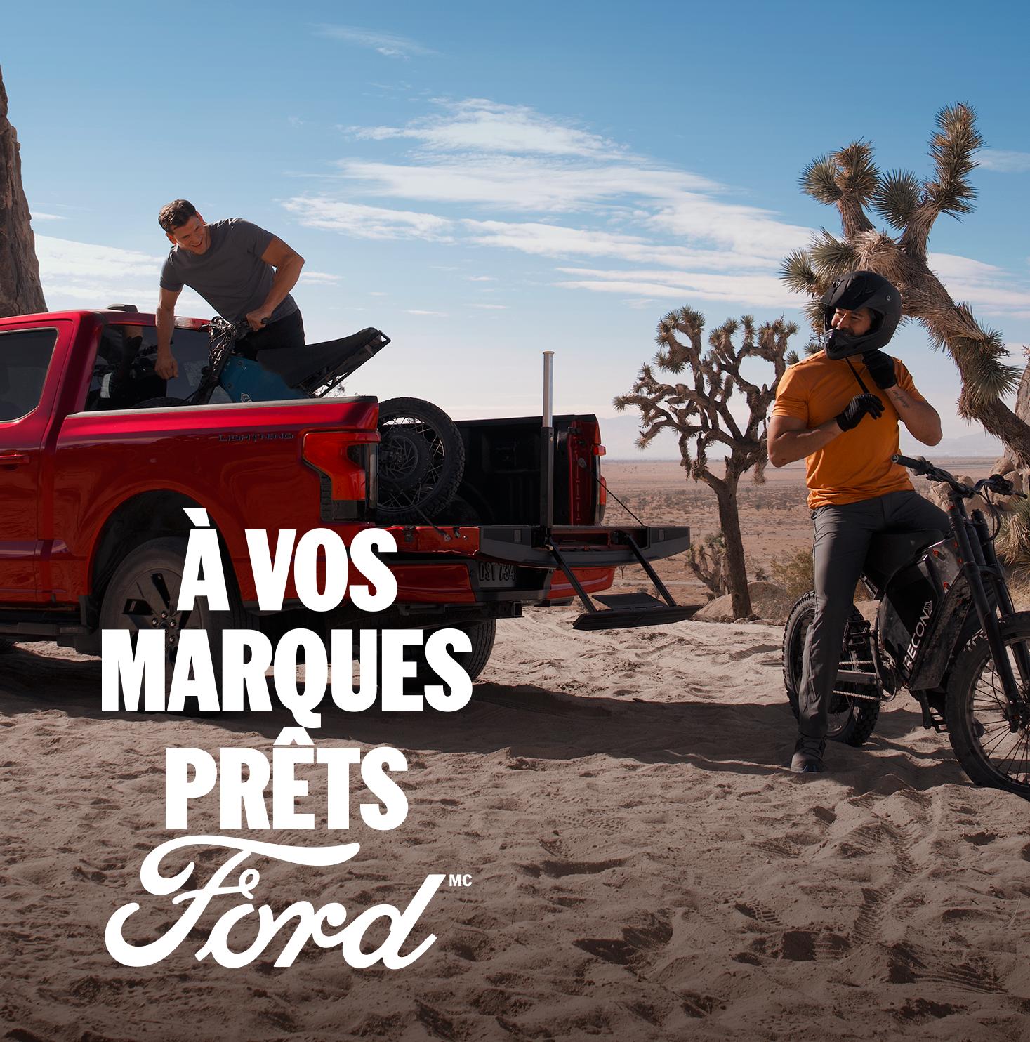 Two people unloading mountain bikes from the bed of a 2025 Ford F-150® Lightning®