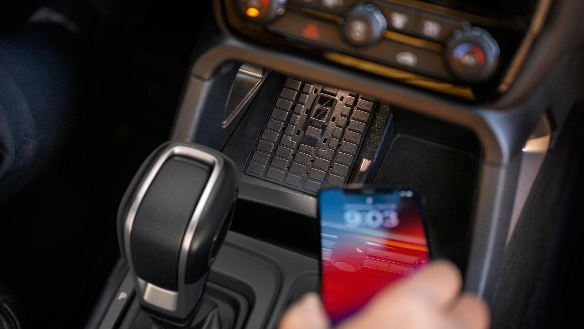 Une personne utilisant le tapis de recharge sans fil à l’intérieur de son camion Ford Ranger® Lariat® 2026