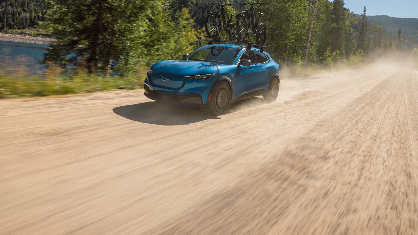 Une Mustang Mach-E® 2027, équipée de l'ensemble sentier en option et du porte-vélos Ford disponible en option, garée hors route