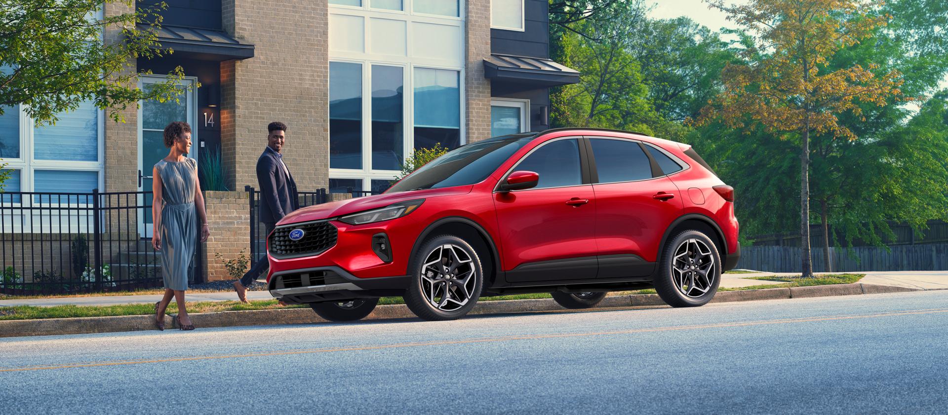 Deux personnes marchant jusqu’à un VUS Ford Escape® 2026 stationné dans une rue de la ville