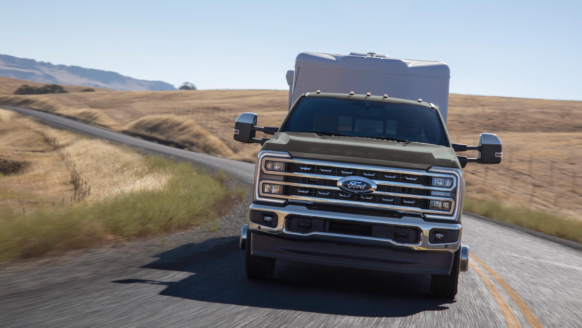 Ford Super Duty® 2026 avec ensemble chromé circulant sur une route pavée vallonnée en tirant une grande remorque