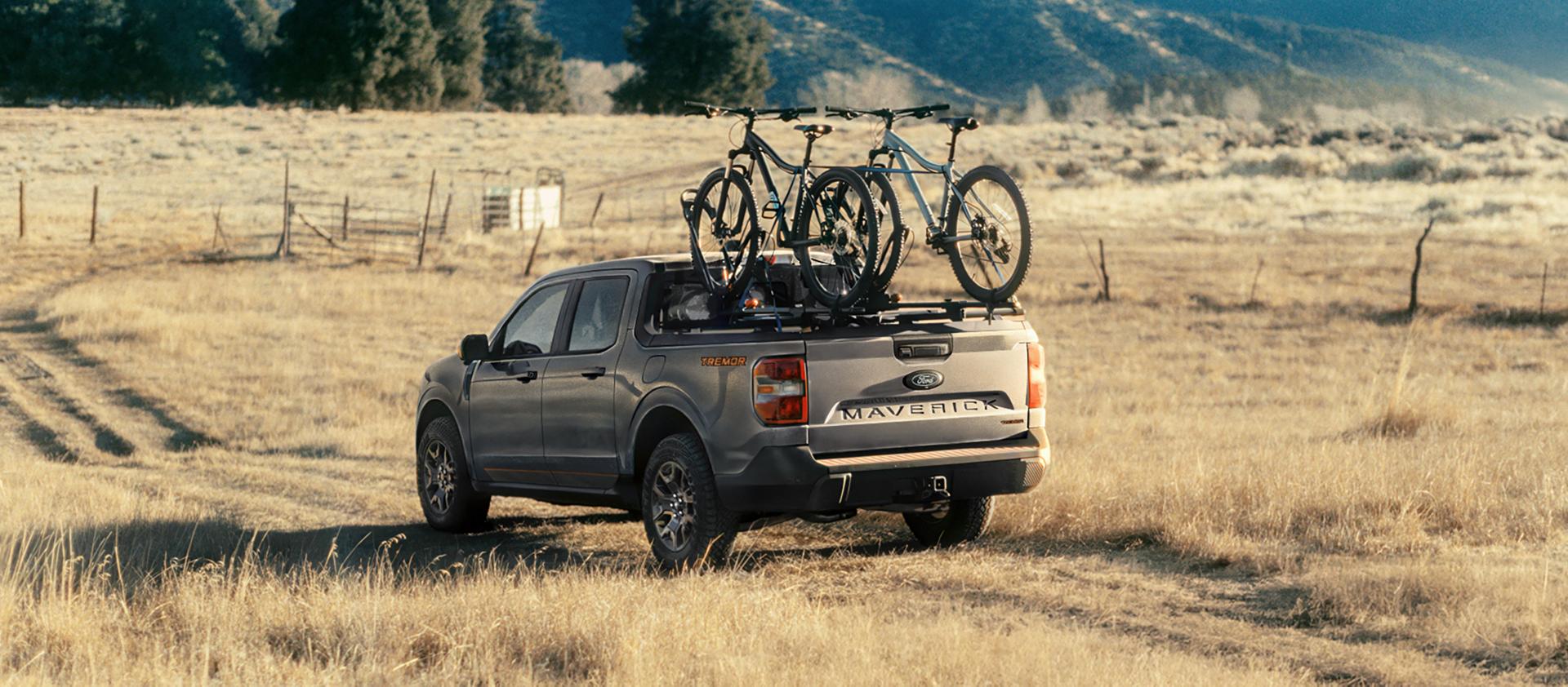 Modèle Ford Maverick® Tremor® 2026 roulant sur un terrain herbeux avec des vélos montés dans la caisse