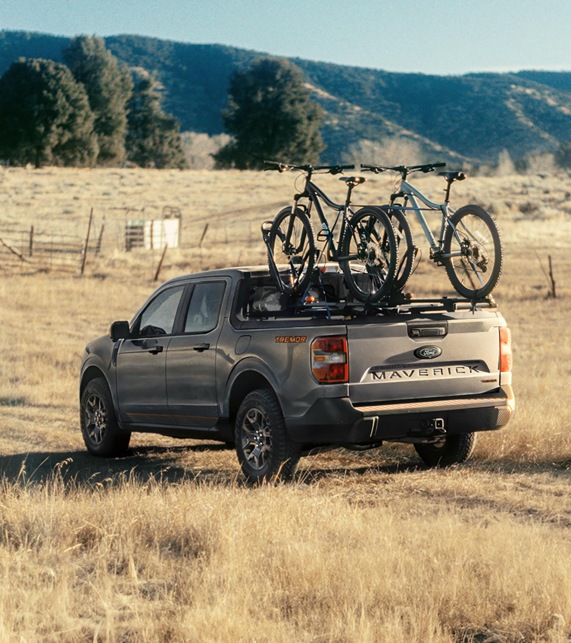 Un Ford Maverick® Tremor® 2026 roule sur un terrain verdoyant avec des vélos montés à l'arrière