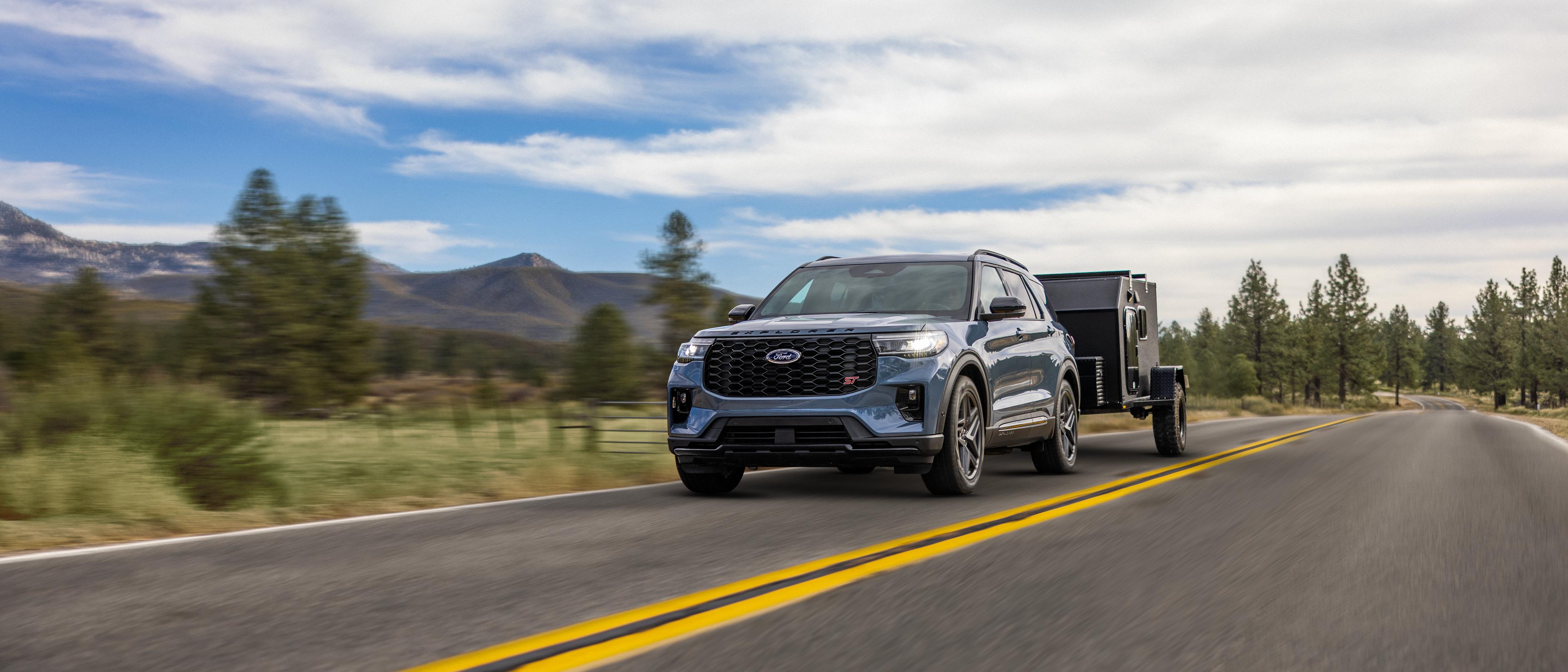 Un VUS Ford Explorer® 2026 tirant une remorque sur une autoroute à travers les montagnes