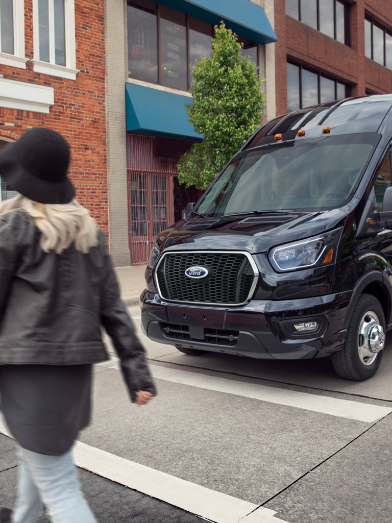 Une fourgonnette Ford Transit® 2026 noire circulant dans une rue de la ville