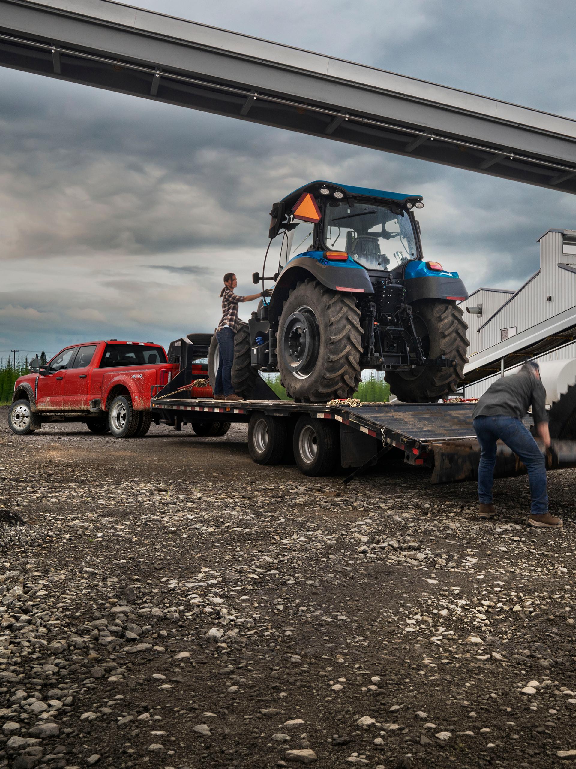 Camionnette Ford Super Duty® F-450® XL 2027 en rouge course tirant une remorque transportant un gros tracteur