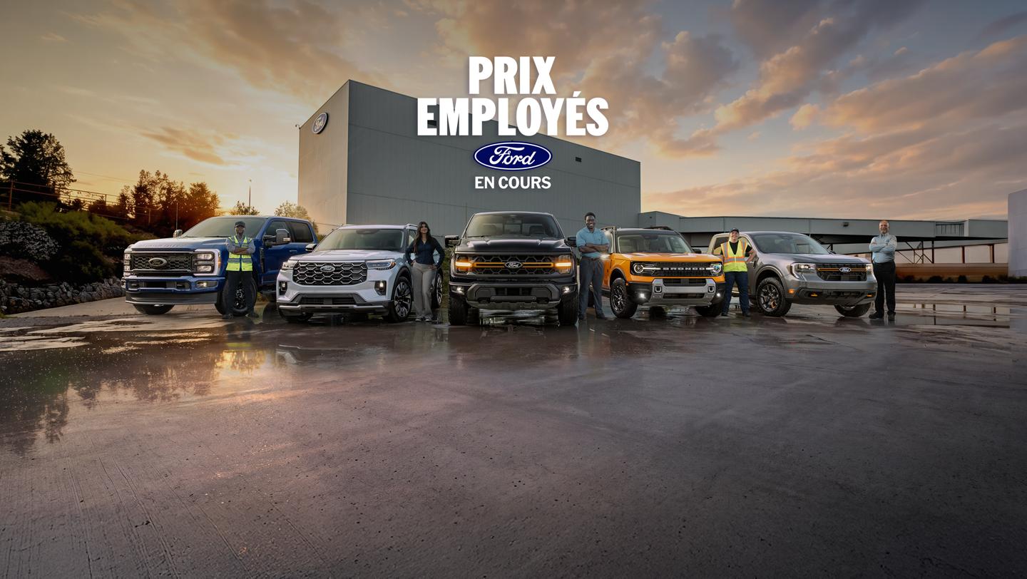 Des employés de Ford debout près de véhicules Ford stationnés devant l’usine d’assemblage Ford d’Oakville.