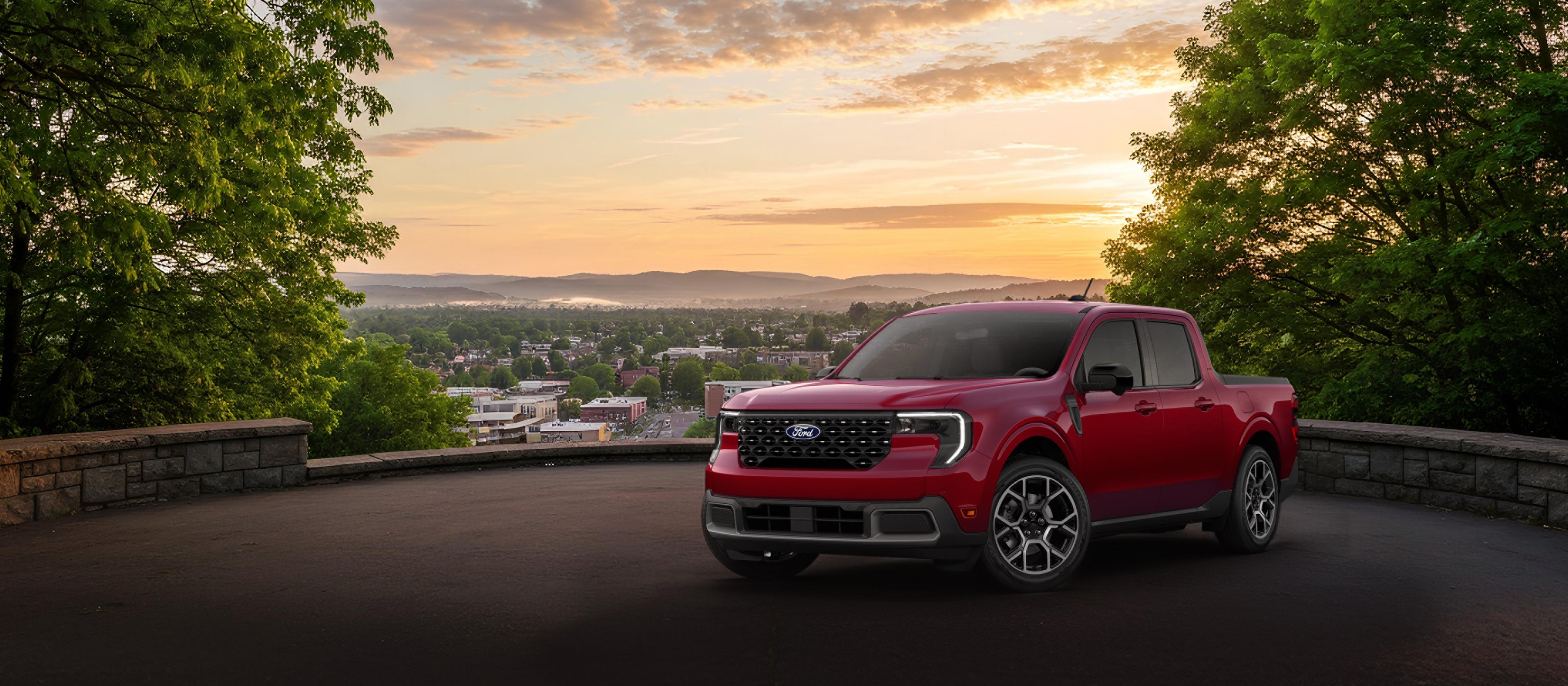 Modèle Ford Maverick® Lariat® 2026 en rouge rubis métallisé avec vernis teint (coût supplémentaire) stationné et surplombant une ville