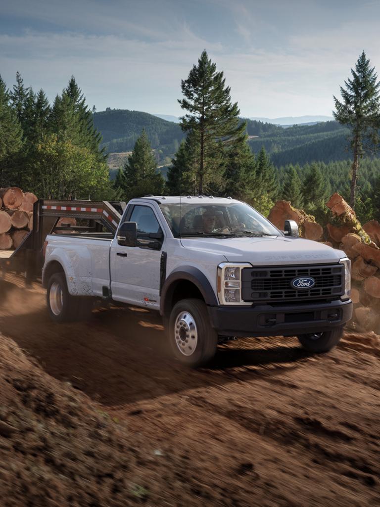 Modèle Ford F-450® Super Duty® XL 2027 avec ensemble décor STX® circulant sur une route de terre