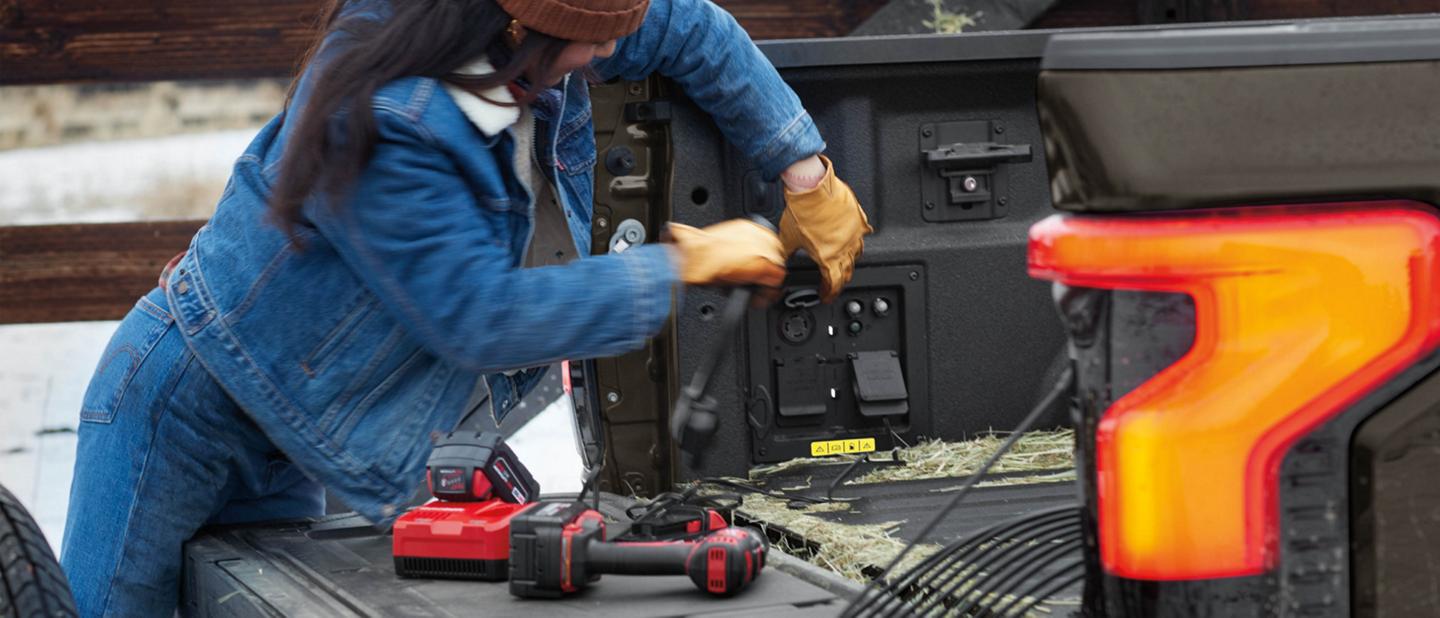 Une femme branche un outil électrique dans une prise située sur le plateau d’un camion de la Série F.